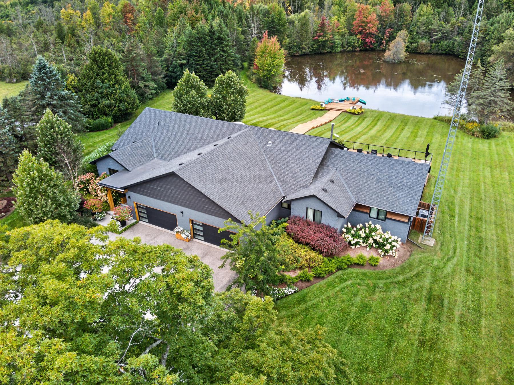 Aerial of the house, the glass rear elevation and the deck above the lawn
